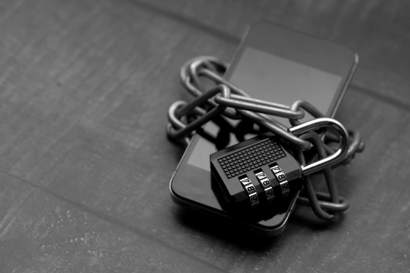 Celular preso com corrente e cadeado, em preto e branco