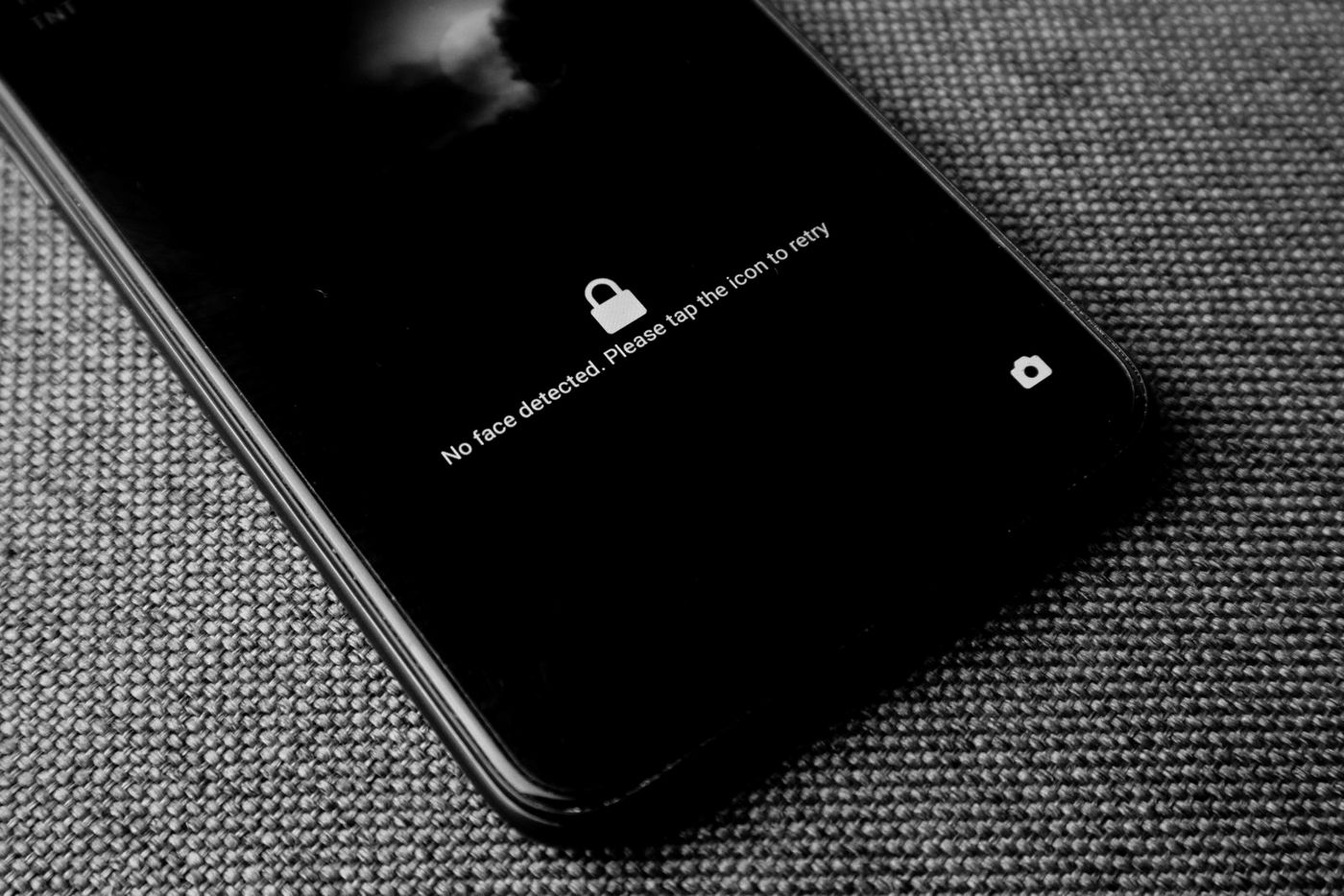 Celular com a tela bloqueada sobre um tecido, em preto e branco