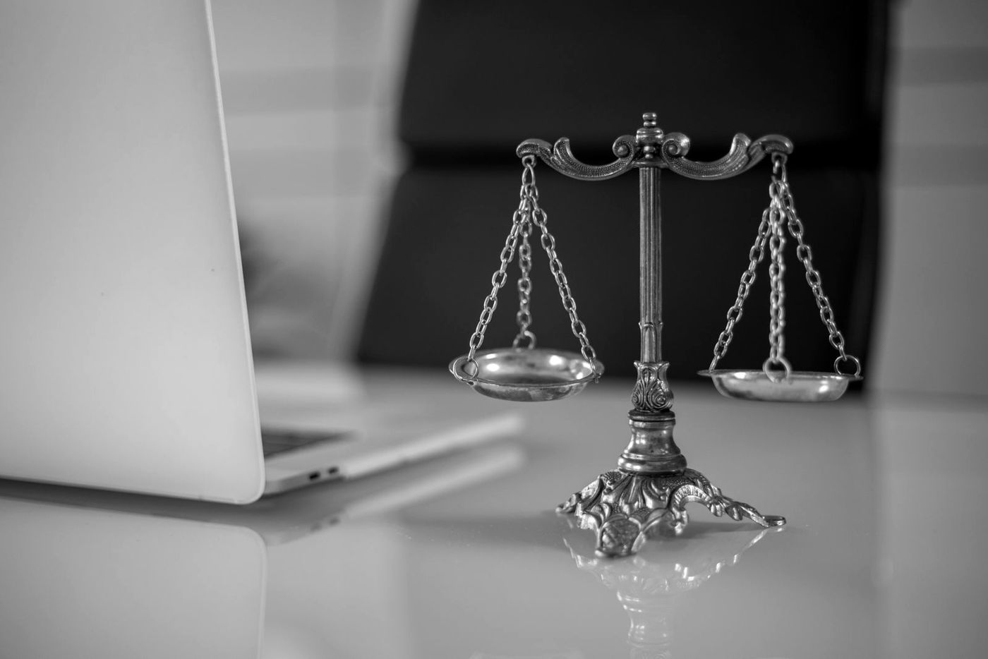 Balança da justiça ao lado de um notebook, em preto e branco