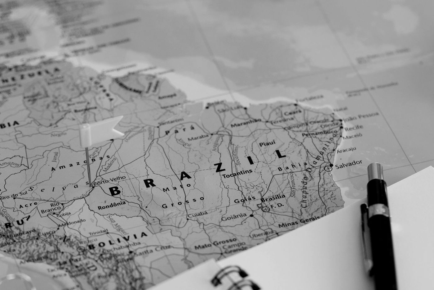 Mapa do Brasil ao lado de um caderno e uma lapiseira, em preto e branco