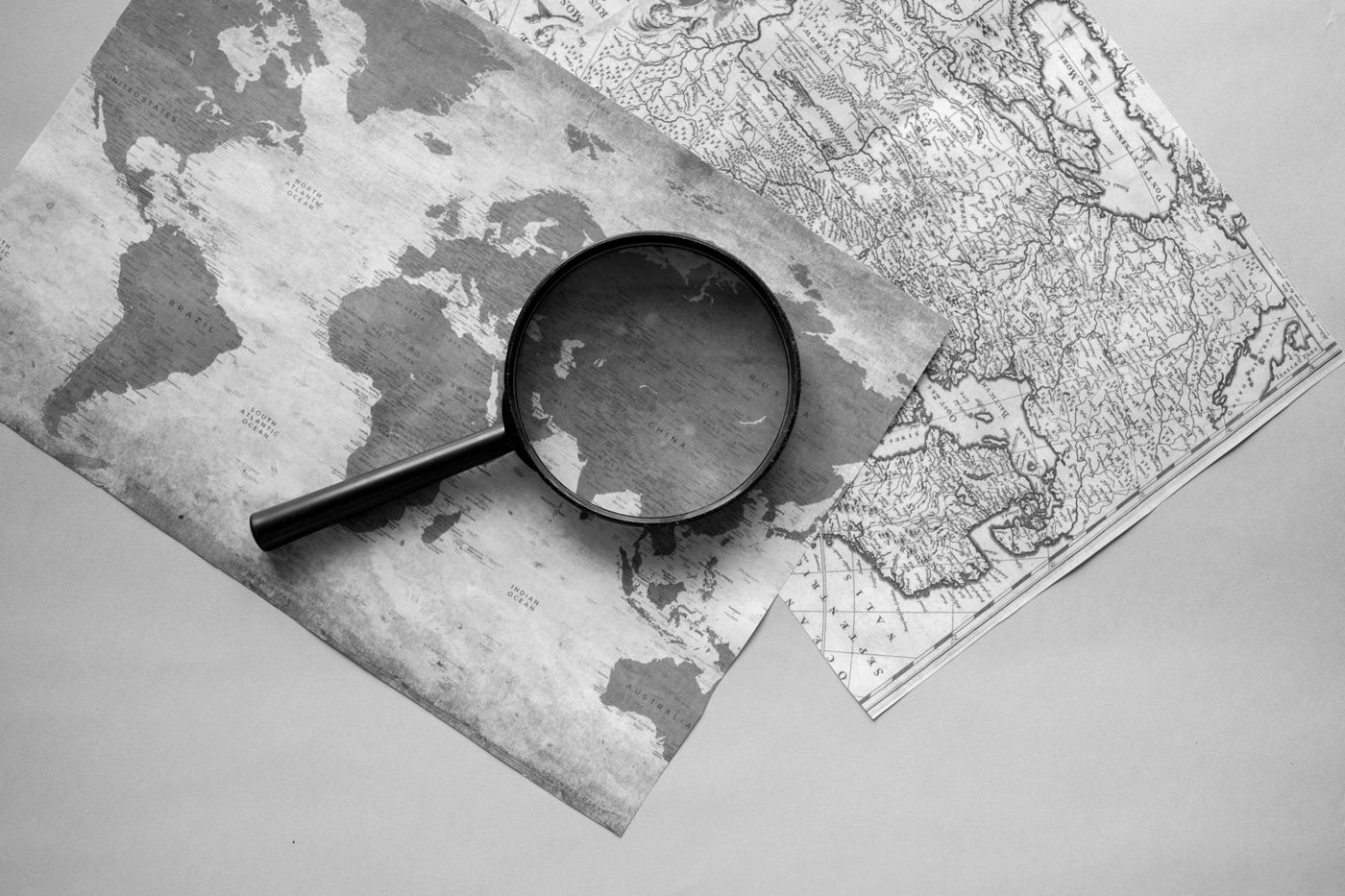 Lupa sobre um mapa-múndi impresso, em preto e branco